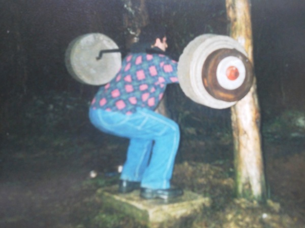 Joe Kinney squats on his self made safety squat bar. The plates were cement which he also made.